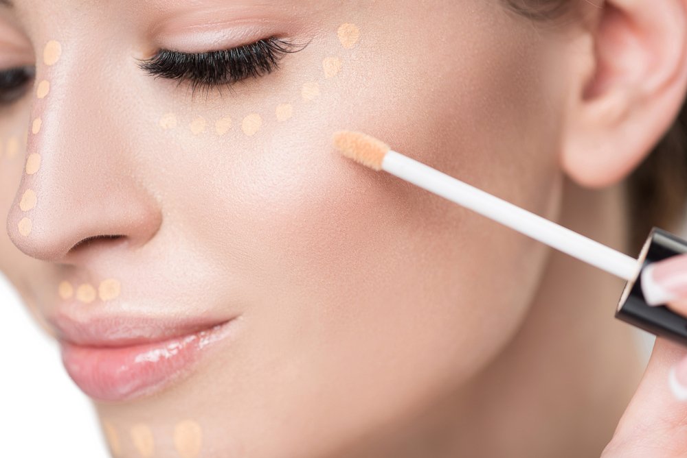 A Lady is applying Concealer. The image showcases the concept of foundation vs concealer application.