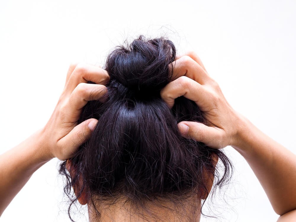 An image of a Woman itching her scalp. 