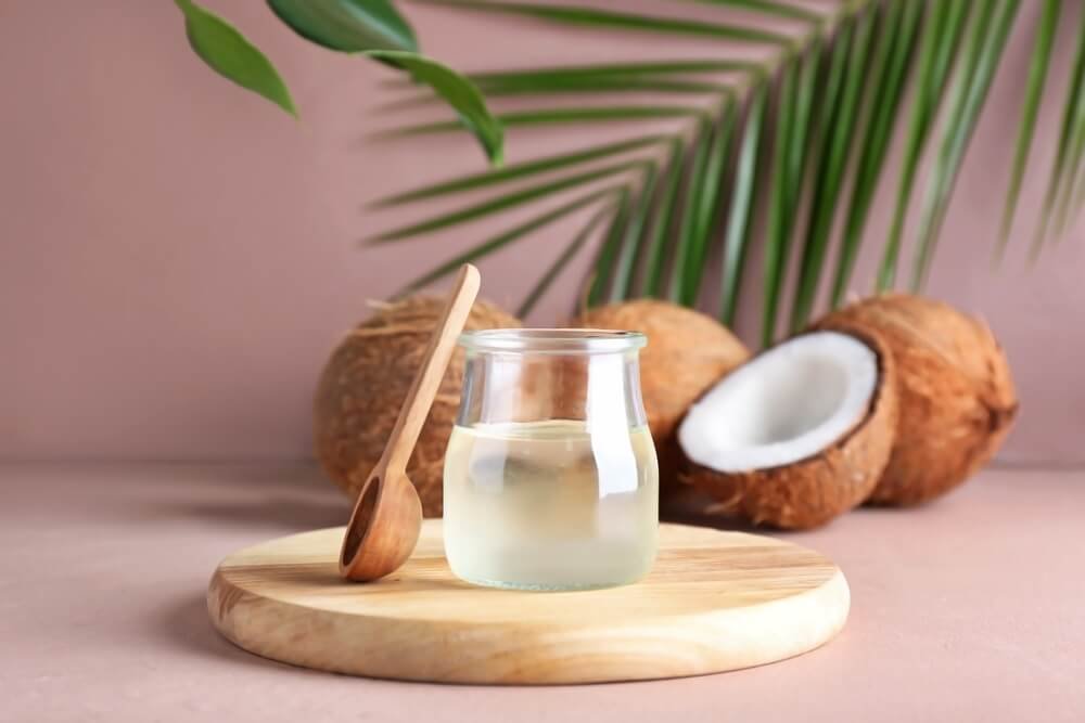 Close-up of coconut oil in a jar with natural coconut pieces, illustrating the skincare benefits of coconut oil.