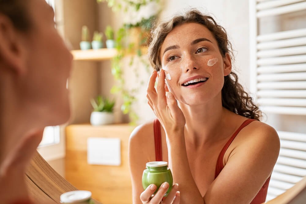 An image showing a woman applying natural skincare product on her fece.